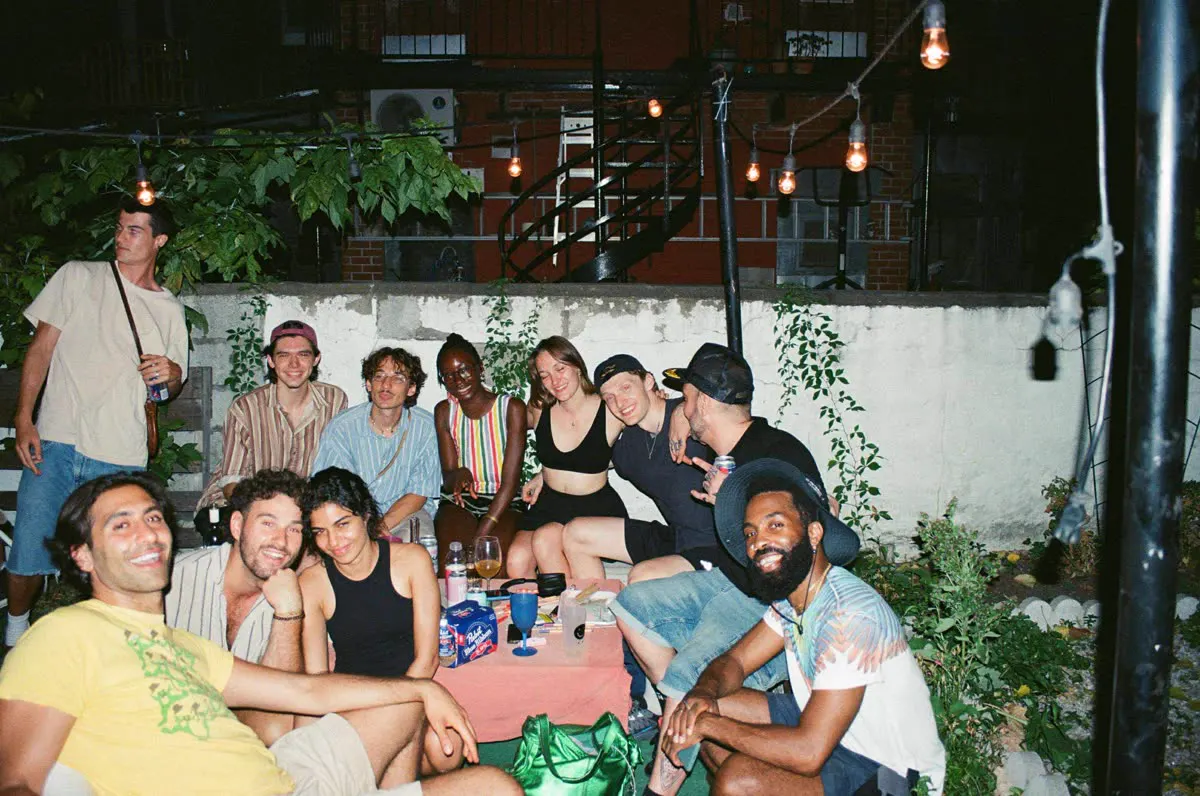 A group of friends at a table in a courtyard lit with string lights