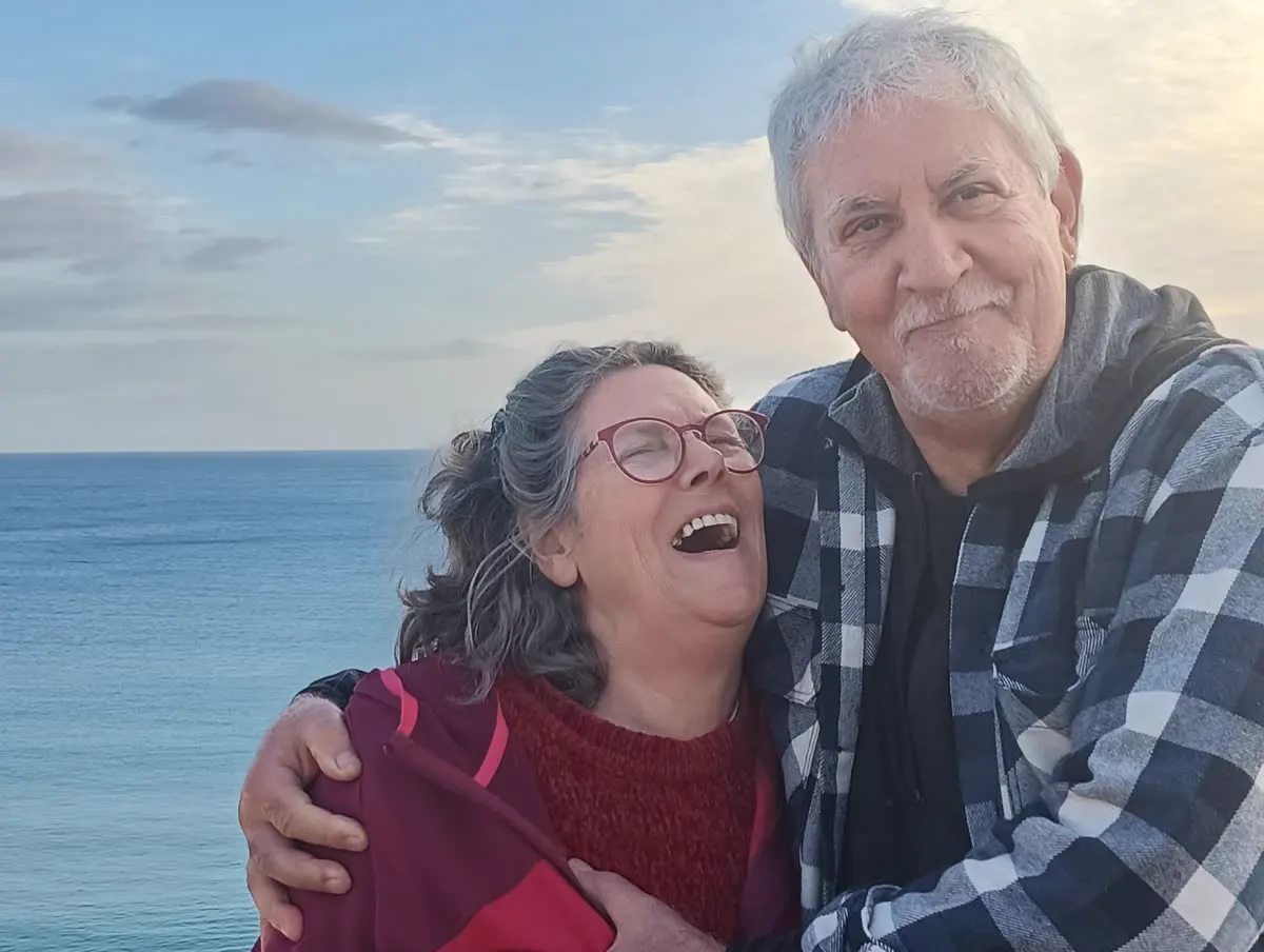 An elderly couple laughing together by the sea