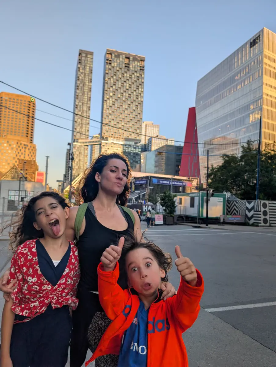 A woman and two children pull faces in front of the Montreal skyline