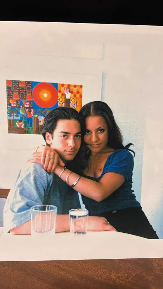 Vintage photo of a couple at a table in front of a colourful poster