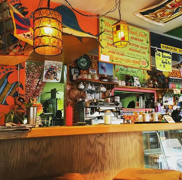 Inside the café: wooden counter, espresso machine and walls covered in colourful posters